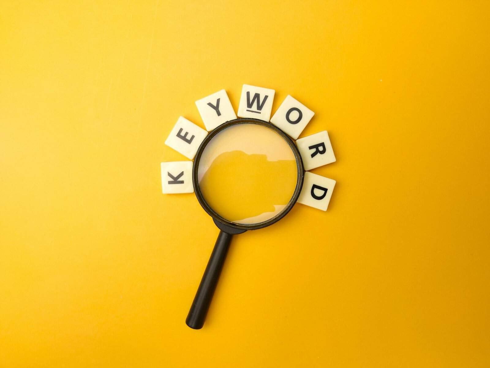 Magnifying glass and toys word with the word KEYWORD on yellow background